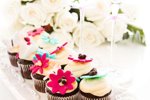 Miniatuur cupcakes versierd met heldere bloemen voor het huwelijksfeest.