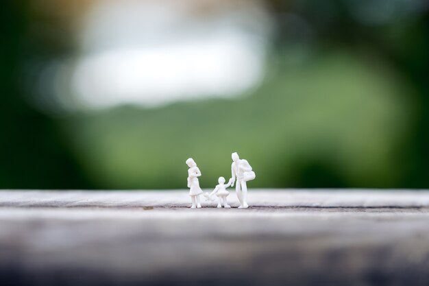 Miniatuur figuur model van vader, moeder en dochter lopen samen op houten tafel