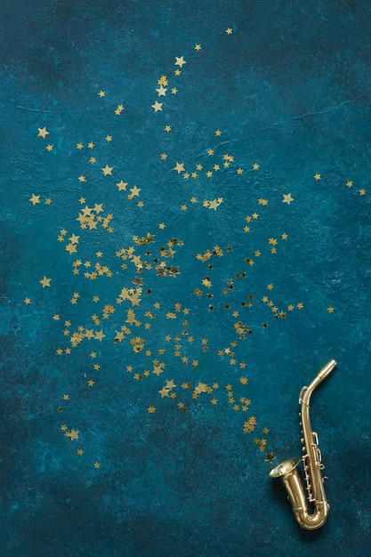 Miniatuur gouden saxofoonexemplaar op de blauwe achtergrond met glitter.