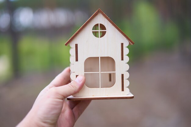 Miniatuur houten huis in een mannenhand