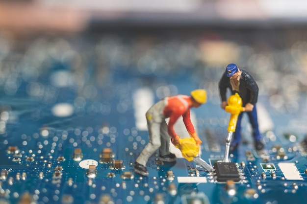 Foto miniatuur mensen: arbeidersteam van ingenieurs die laptop van de toetsenbordcomputer herstellen