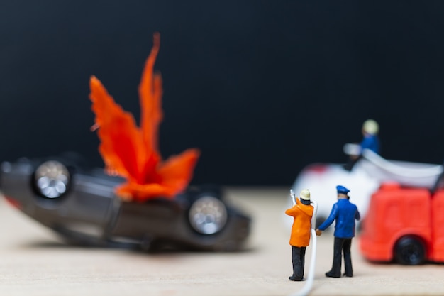 Miniatuur mensen: brandweerlieden bij een auto-ongeluk