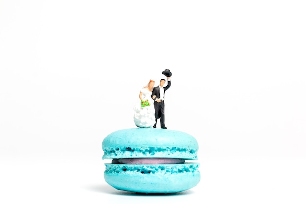 Miniatuur mensen, bruid en bruidegom op kleurrijke franse macaron,