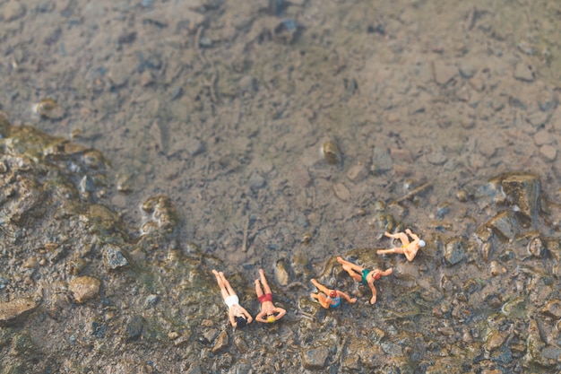 Miniatuur mensen die zwempak het ontspannen op het strand dragen