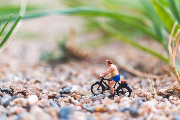 Miniatuur mensen: reizigers fietsen op het zand