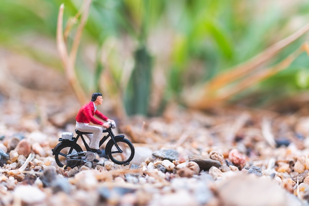 Miniatuur mensen: reizigers fietsen op het zand