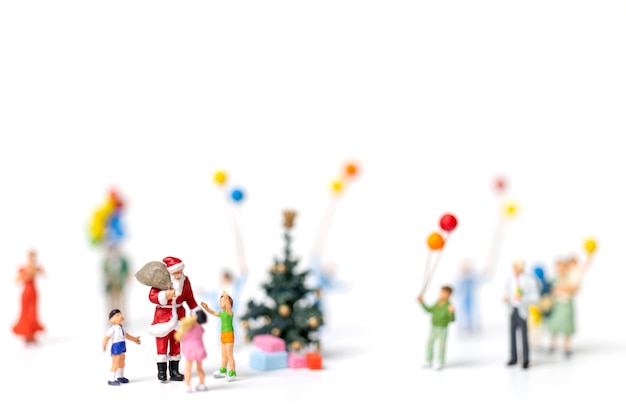 Miniatuur mensen: Santa Claus holding cadeau voor gelukkige familie