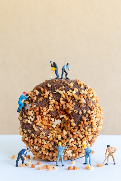 Miniatuur mensen werkend team dat zelfgemaakte chocolade butternut donuts maakt