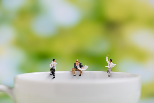 miniatuur met krant zitten op een koffiekopje