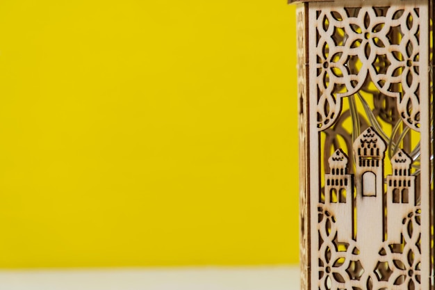 Foto miniatuur moskee gemaakt van hout met gele achtergrond witruimte voor tekst ramadhan kareem