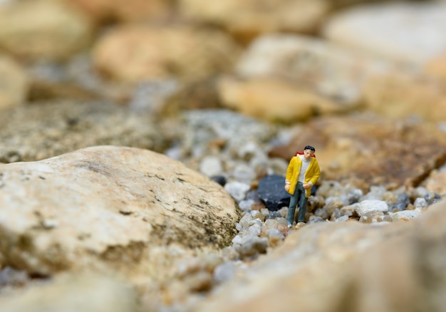 Miniatuur rugzakreizigers die rots, reisconcept wandelen