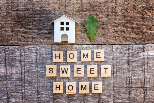 Miniatuur speelgoed model huis met inscriptie HOME SWEET HOME letters woord op houten achtergrond