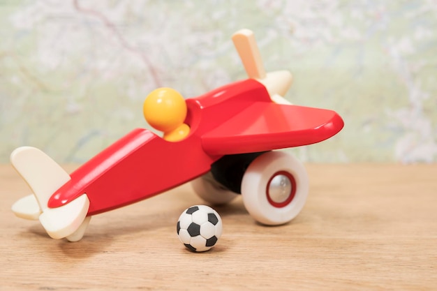 miniatuur voetbal op een speelgoedvliegtuig liggend op een houten tafel op een achtergrondkaart