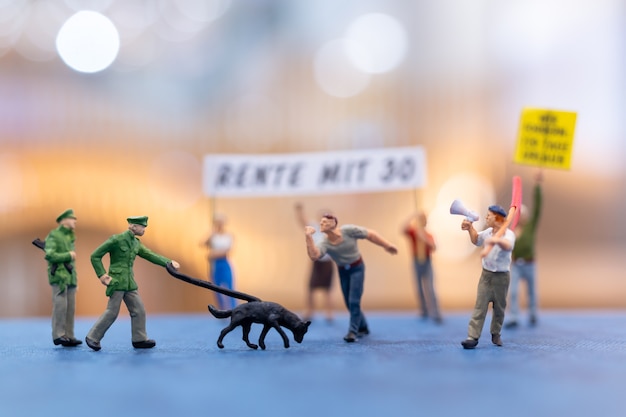 Miniatuurdemonstranten die borden vasthouden en protesteren met onscherpe achtergrond