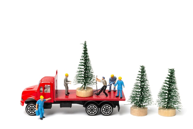 Miniatuurmensen, arbeider die kerstboom op witte achtergrond, Kerstmis en gelukkig Nieuwjaarconcept voorbereiden.