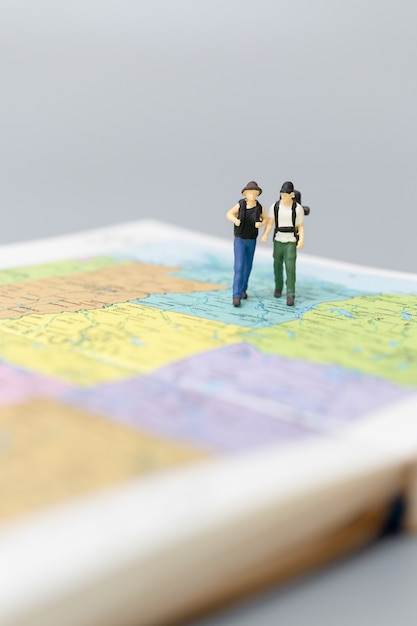 Foto miniatuurmensen backpacker die op kaart loopt reis- en avontuurconcepten.