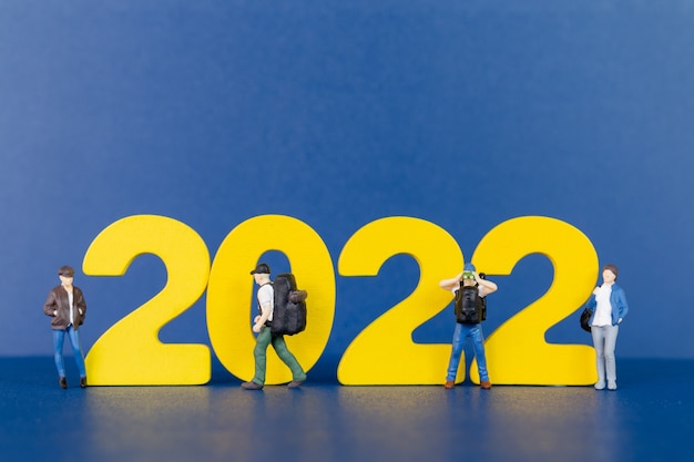 Miniatuurmensen backpacker die zich op houten nummer 2022 bevinden, Gelukkig nieuw jaarconcept