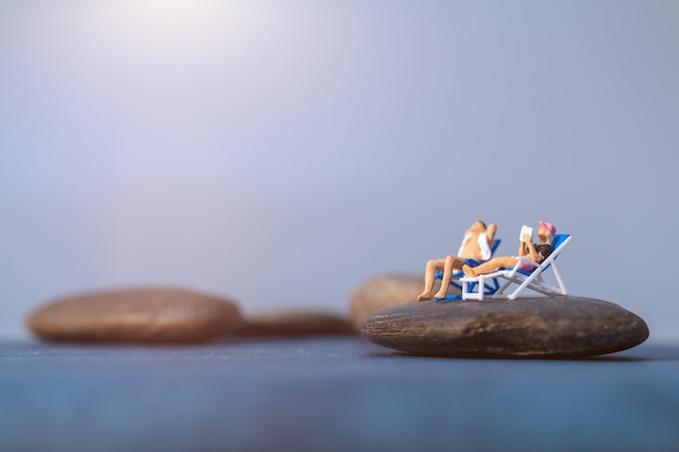 Miniatuurmensen die op het strand, het concept van de zomertijd zonnebaden