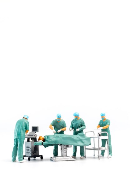 Foto miniatuurmensen dokter die een patiënt opereert op een witte achtergrond