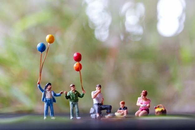 Miniatuurmensen: Gelukkige familie zittend op de mat tijdens een picknick in een park