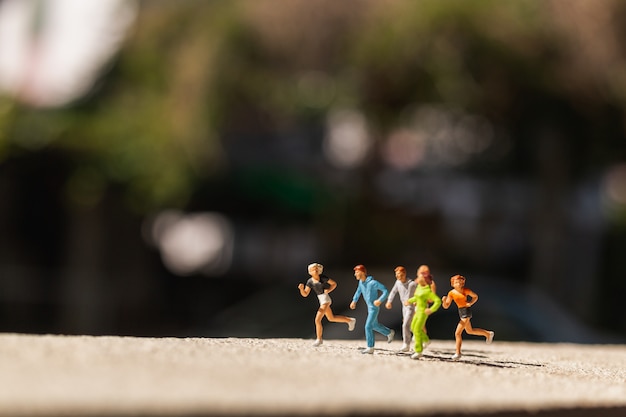 Foto miniatuurmensen: groep mensen loopt op betonweg