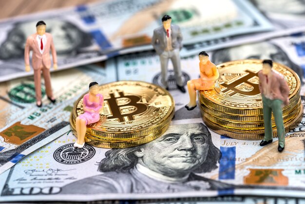 Miniatuurmensen met bitcoins en dollars