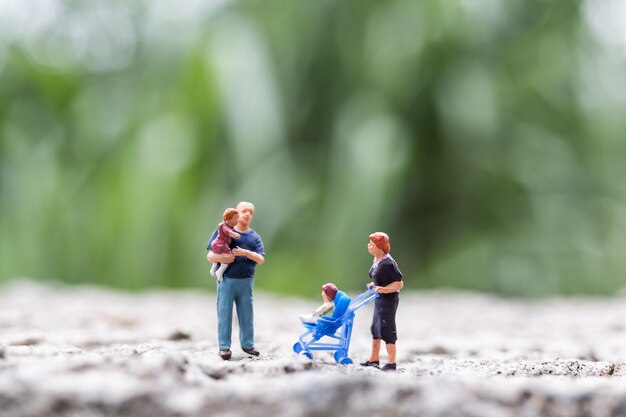 Miniatuurmensen Ouders met kinderen die buiten lopen