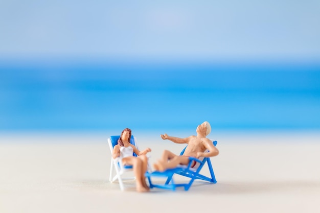 Foto miniatuurmensen paar ontspant zich op strandstoelen op het strand