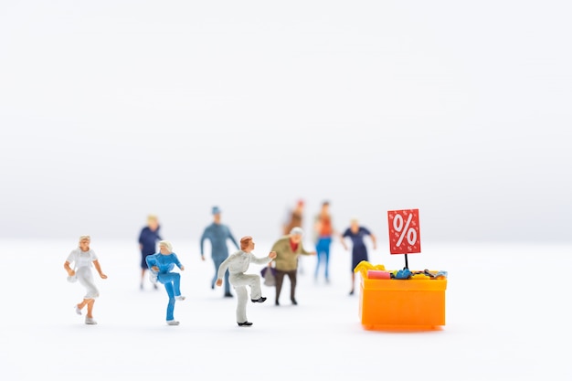 Miniatuurmensen, shoppers die naar een kortingsvak rennen om te winkelen met korting op artikelen