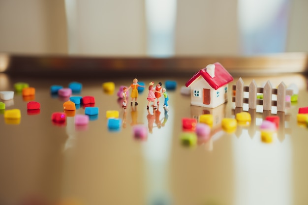 Miniatuurmensen, spelende kinderen die thuis als familie en onderwijsconcept gebruiken