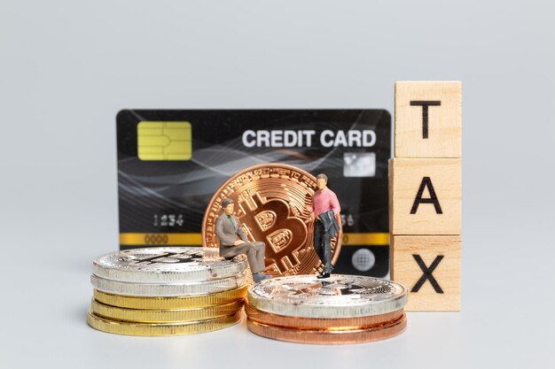 Miniatuurmensen, zakenman met Crypto-valuta en houten letters TAX op grijze achtergrond, Bitcoin-investeringen en belastingenconcept.