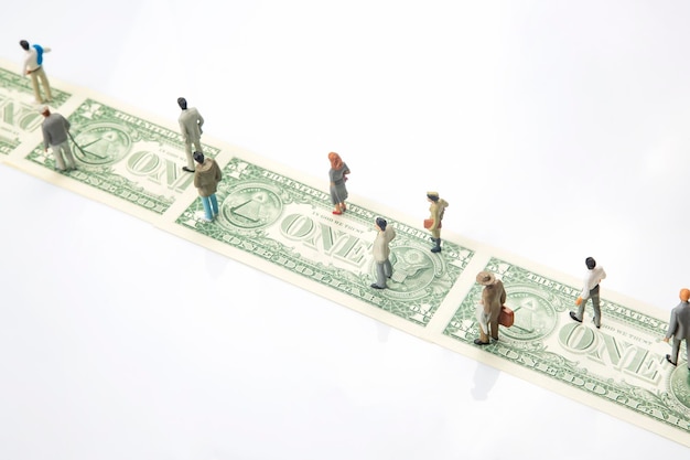 Miniatuurmensenbeeldjes van mensen lopen de weg van dollargeld naar hun succes in het concept van financiële onafhankelijkheid van het leven