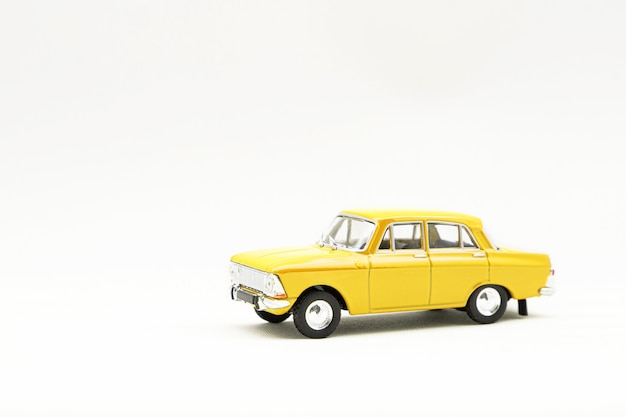 Miniatuurmodel van een gele retro auto op een witte ondergrond