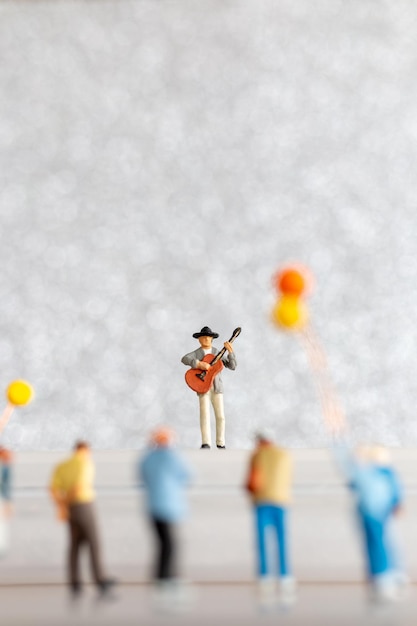 Foto miniatuurmuzikant die gitaar speelt op het podium wereldmuziekdagconcept
