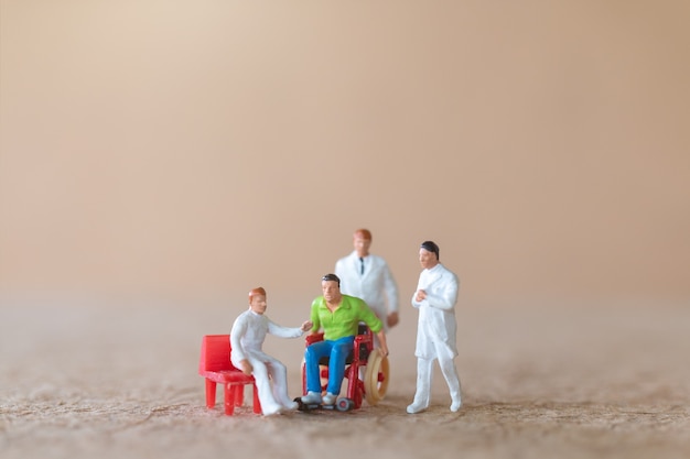 Miniatuurpatiënt in rolstoel overleg met artsen op lichte achtergrond