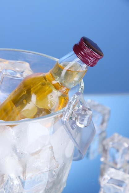 Minibar bottles in bucket with ice cubes on color background