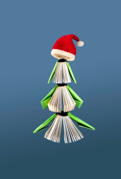 Miniboeken in groene omslagen en kerstmuts die op een blauw kerstdecor als achtergrond vliegen