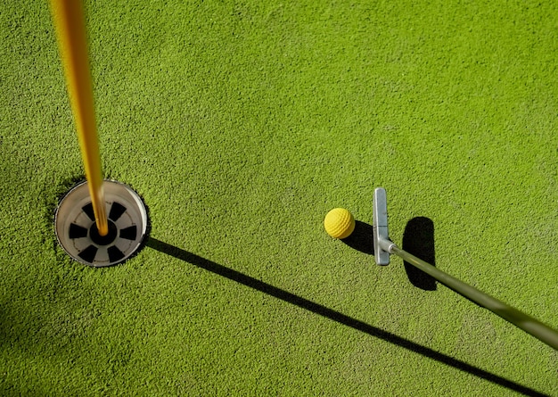 Minigolf gele bal met een vleermuis bij het gat bij zonsondergang