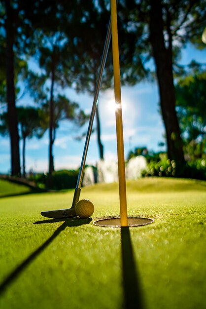 Minigolf gele bal met een vleermuis bij het gat bij zonsondergang