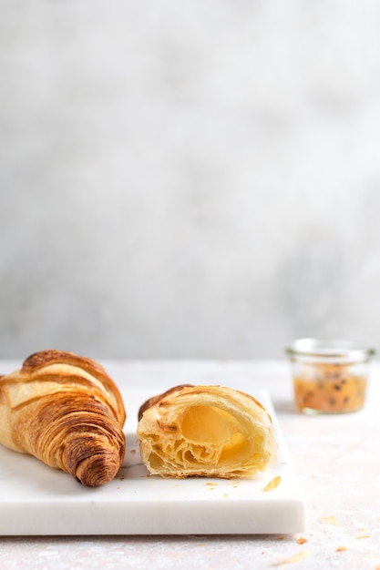 Foto minimaal ontbijt versgebakken croissant met passievruchtenjam op marmeren bord