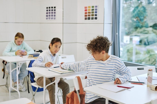 Minimaal portret van drie kinderen in de rij die een briefje doorgeven in de klas van de school