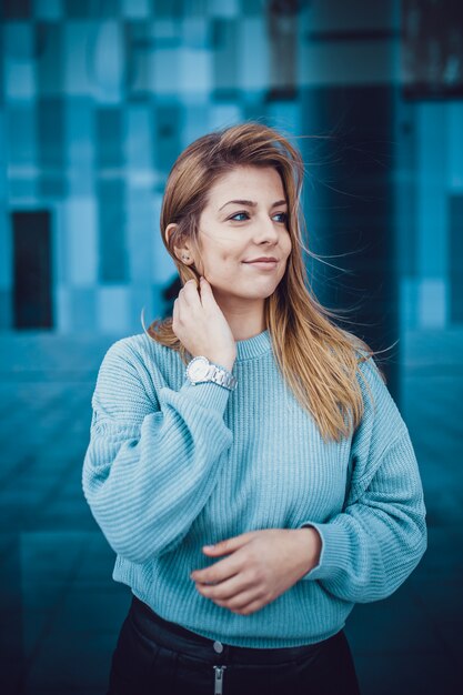 Minimaal portret van een mooi jong meisje dat zich tegen blauwe muur bevindt