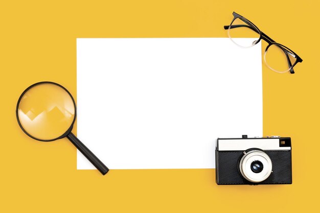 Minimal background with blank paper camera and magnifier flat lay