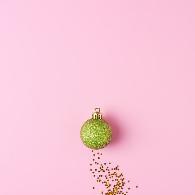 Minimal Christmas background with bauble and confetti on pink