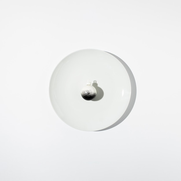 Minimal Christmas composition Black and white bauble on white plate