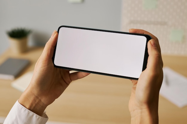 Photo minimal close up female hands holding phone with white screen mock up