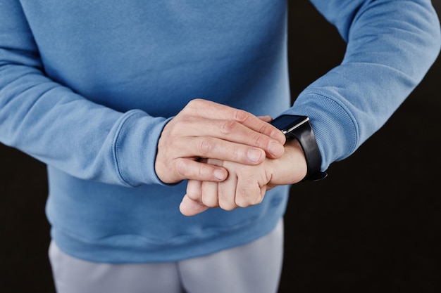 Minimal closeup of man checking smartwatch against black background copy space