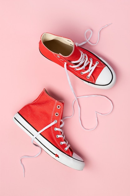 Минимальная композиция с красными кроссовками на розовом фоне