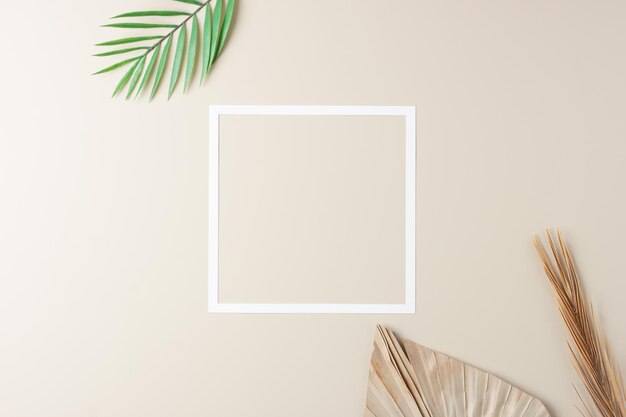 Minimal composition with white frame and palm leaf on pastel beige background Flat lay copy space