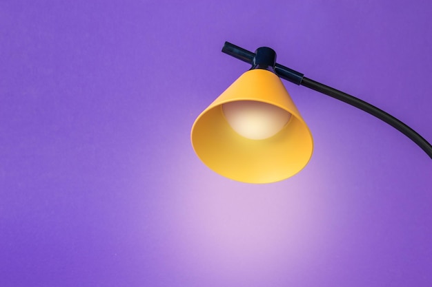 Minimal concept Yellow table lamp on a purple background